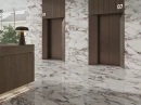 Elegancka przestrzeń hotelowego holu z drewnianą recepcją,  windami oraz białymi marmurowymi ścienno-podłogowymi płytkami z bordowymi żyłami w połysku  FANAL CALACATTA VIOLA 60x120 SSHINE BRILLO N13C3