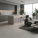Salon z kuchnią w kolorze szarym z płytkami antypoślizgowymi, hiszpańskimi, imitującymi beton Cifre Acron Pearl Mate Antislip 120x120, z wyspą kuchenną, hokerami, ozdobym oświetleniem, kanapą, okrągłym stolikiem i dywanem.