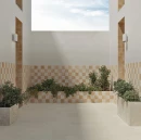 Aranżacja nowoczesnego patio z białą płytką gresową WOW Halo S Dawn 11x11 cm (132945) ułożoną w szachownicę z beżowymi kafelkami na ścianach i donicach. Wnętrze z bujną roślinnością, jasną podłogą i otwartym sufitem.