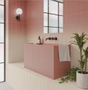 Nowoczesna łazienka z podłużnymi płytkami WOW Melange Cream Earth 10,7x54,2 cm (132675) ułożonymi pionowo z efektem ombre od brudnego różu do beżu. Różowa umywalka, czarna armatura, lustro i zielone rośliny doniczkowe.