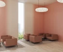 Jasna przestrzeń salonu z płytkami WOW Melange Talc 10,7x54,2 cm (132670) ułożonymi poziomo na filarach przy oknie. Wnętrze z miedzianoróżowymi ścianami, skórzanymi fotelami, wiszącą lampą oraz jasną podłogą imitującą drewno.