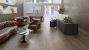 Wnętrze recepcji hotelowej ze skórzanymi sofami i fotelami oraz brązowymi płytkami drewnopodobnymi Porcelanosa Ice Minnesota Moka