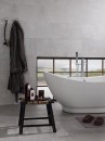 Łazienka z białą wanną wolnostojącą i szarymi płytkami imitujacymi kamień Porcelanosa Dover Acero