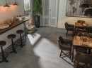 Wnętrze kawiarni ze skórzanymi fotelami, drewnianymi stolikami i szarymi płytkami podłogowymi imitującymi kamień Porcelanosa Boston Stone